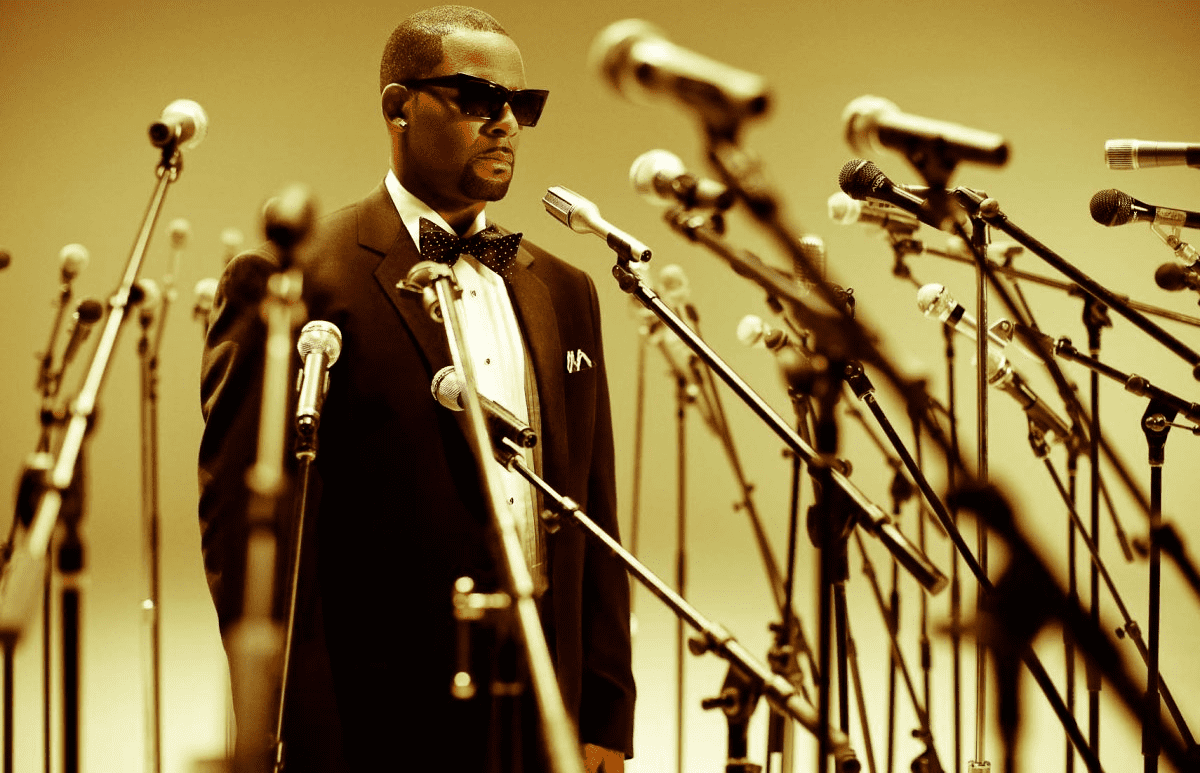 A man in a tuxedo standing in front of microphones.