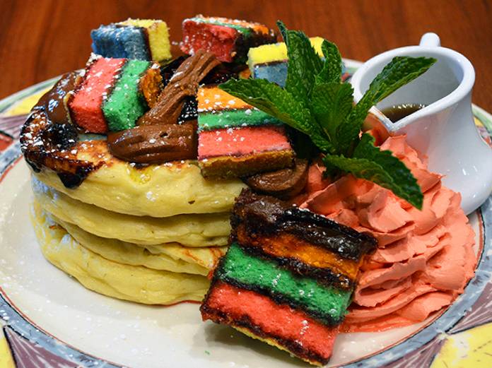 A stack of pancakes with colorful toppings on a plate.
