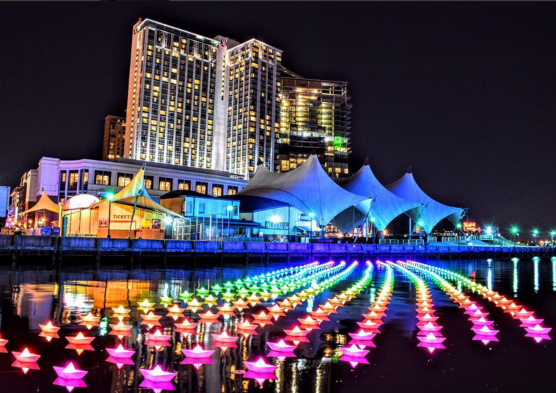 A large group of colorful lights in the water near a building.