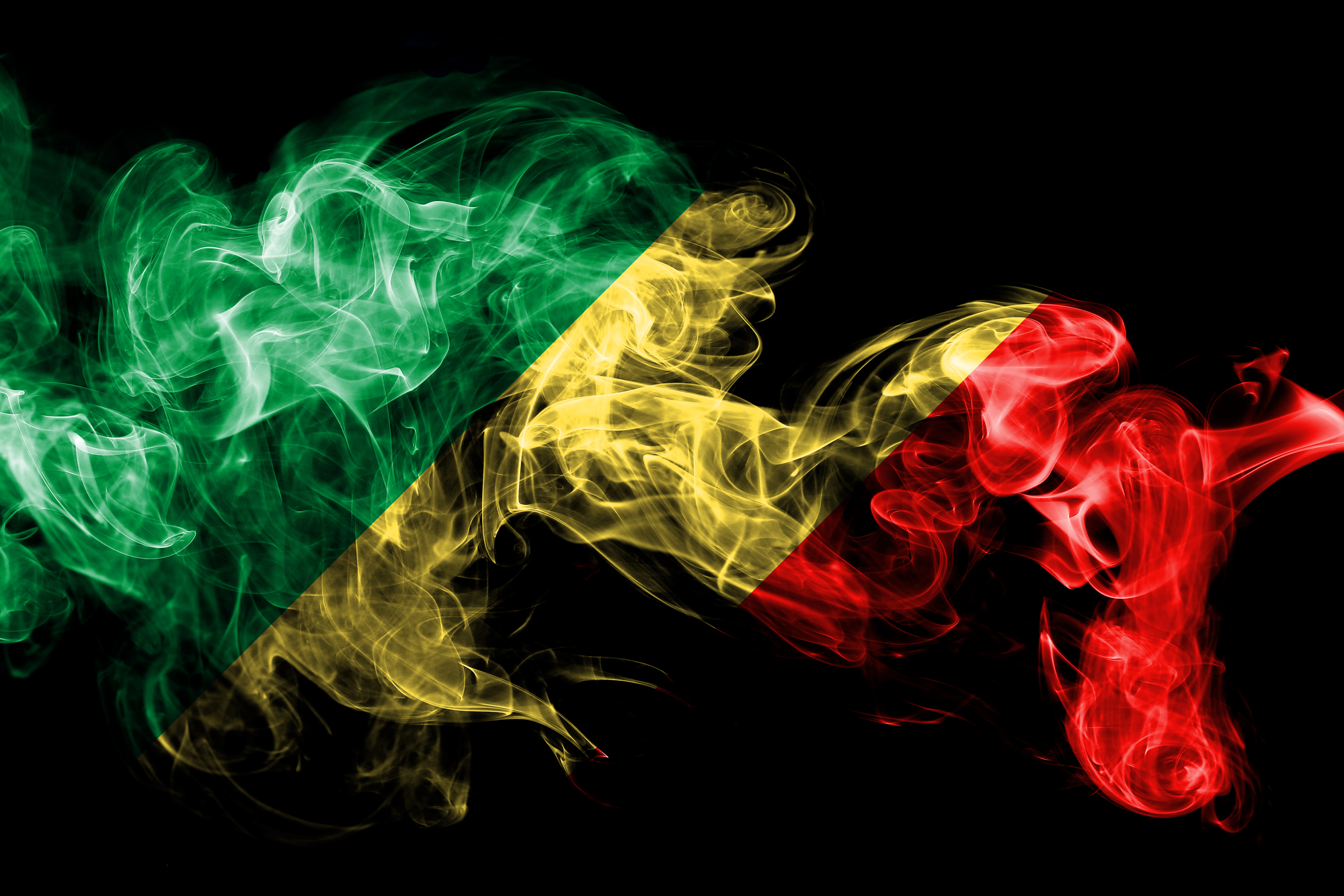 National flag of Congo made from colored smoke isolated on black background. Abstract silky wave background.