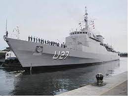 A navy ship docked at a dock.