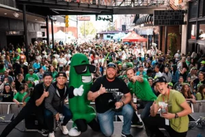 A group of people posing for a photo with a green mascot.