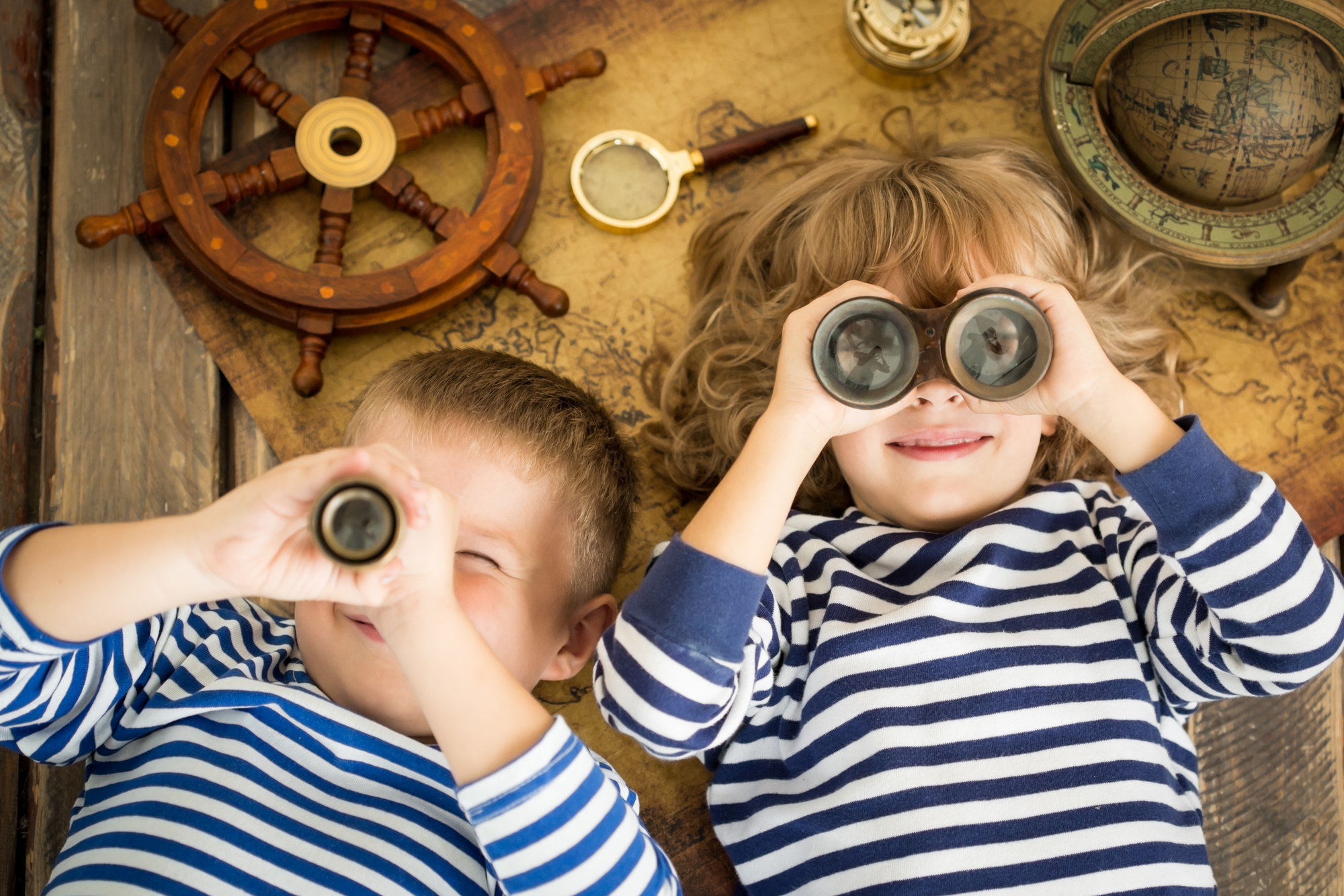 Two boys gazing through binoculars on a wooden table near Harbor Park Garage.