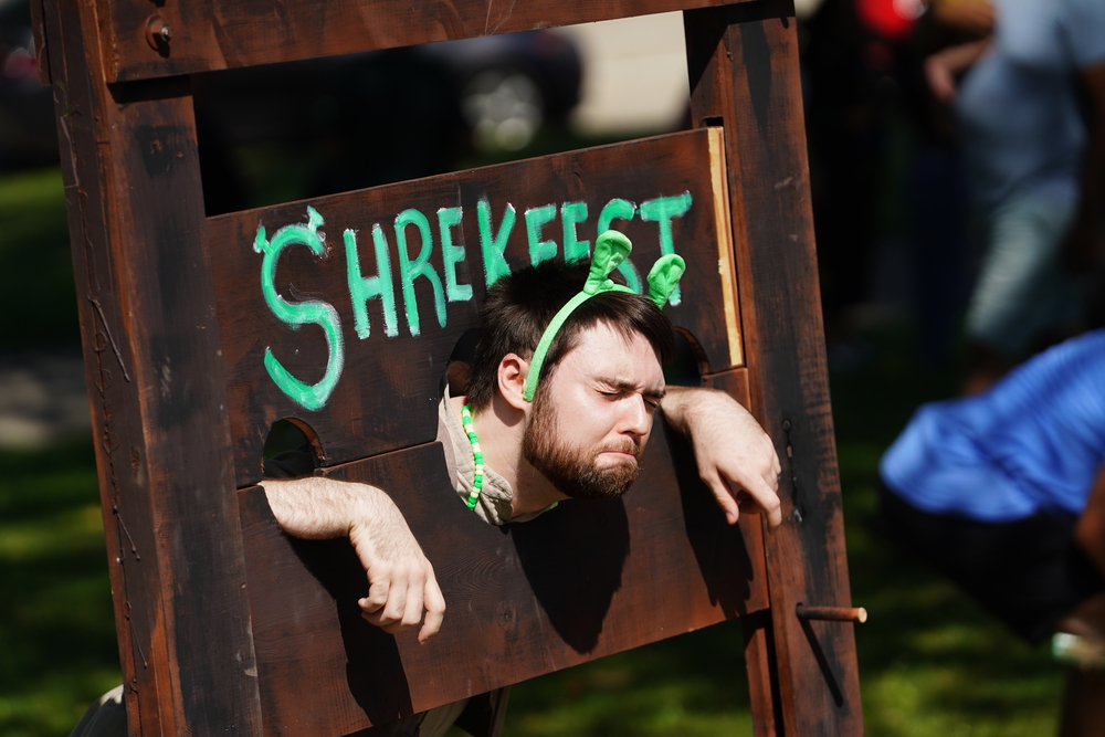A man is leaning against a wooden sign that says ShamrockFest at Baltimore Soundstage.
