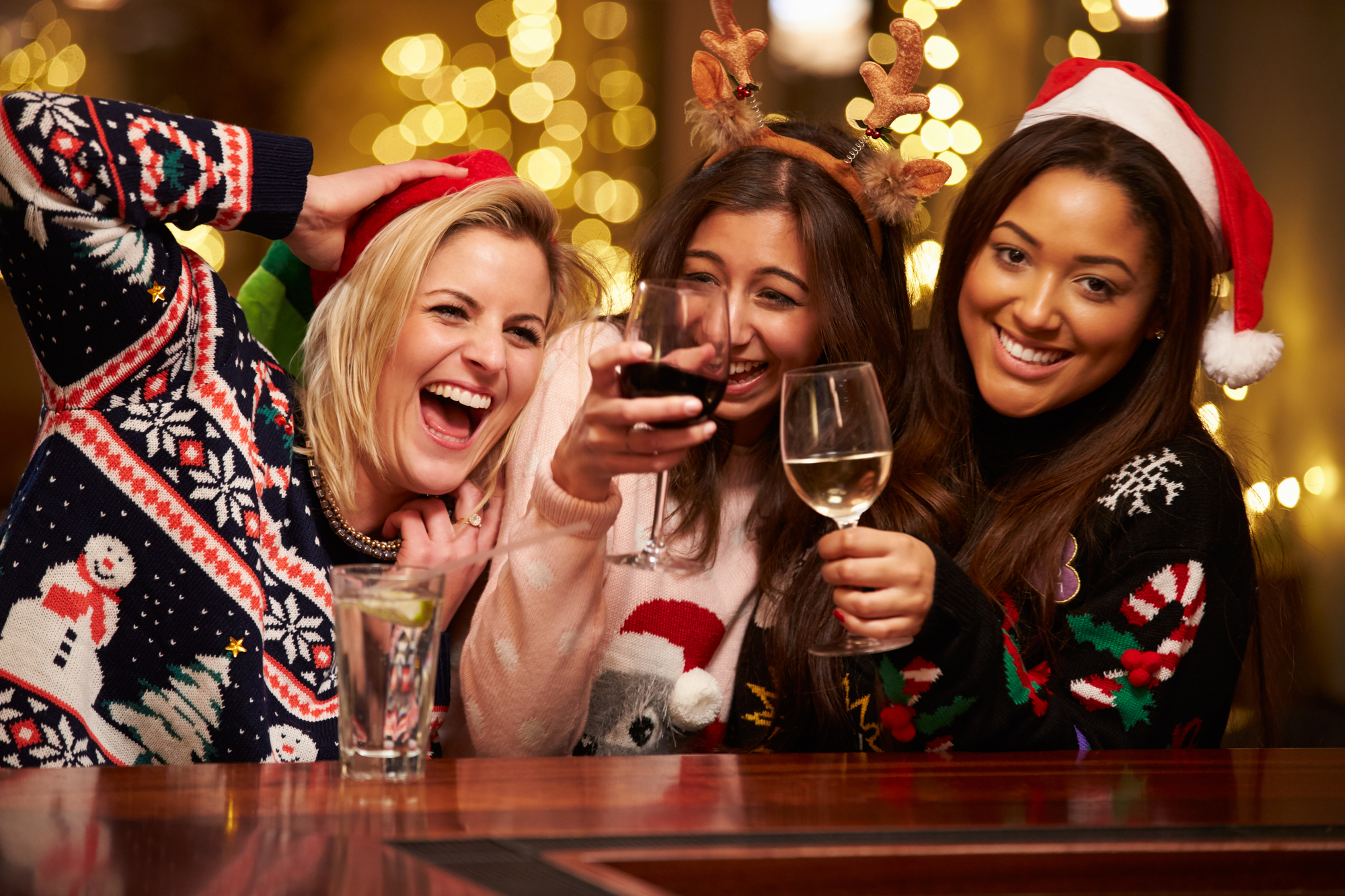 Three women in Christmas hats enjoying wine at a bar in Power Plant Live during the 12 Bars of Charity event.