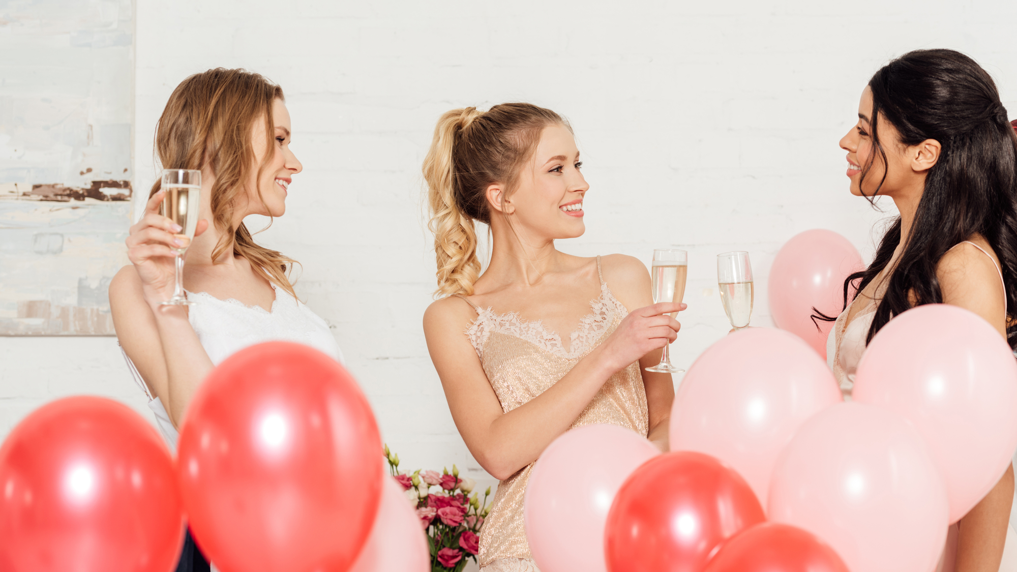 A group of women holding champagne glasses and balloons at a special event.