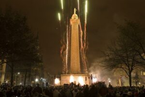 A large group of people watching fireworks in front of the Federal Hill monument in Baltimore during a holiday celebration.
