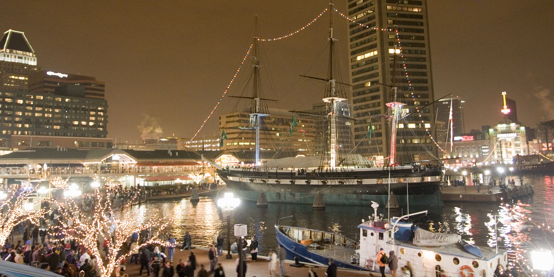 A boat docked in Baltimore's Inner Harbor with holiday lights illuminating its voyage.