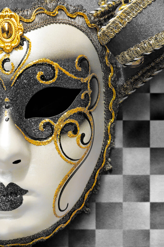 A black and gold venetian mask on a Mardi Gras Live checkered background.