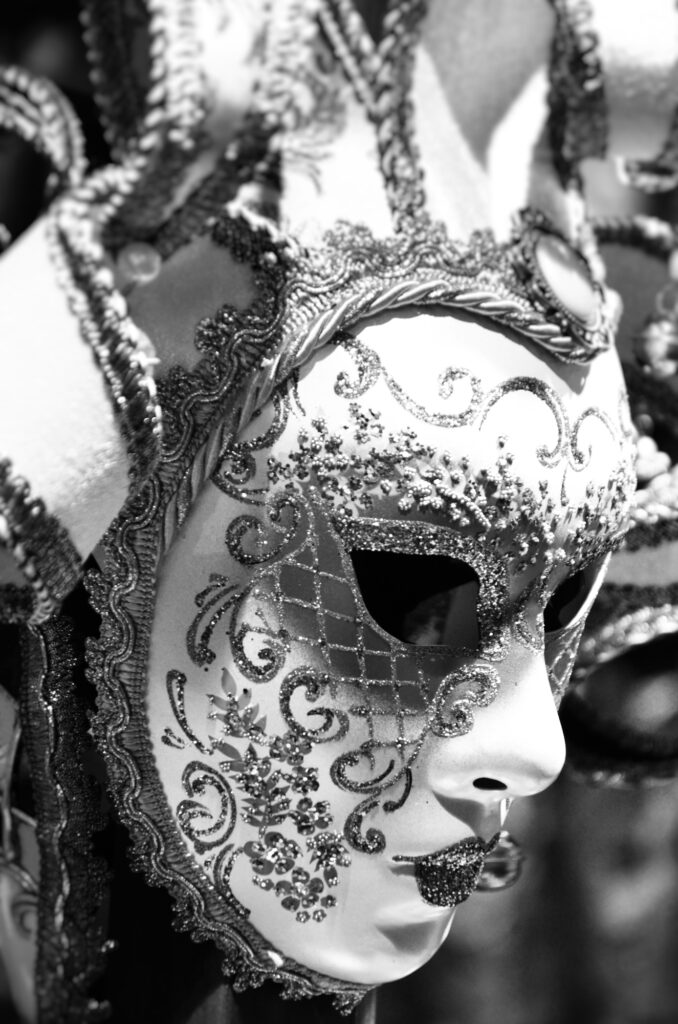 A black and white photo of a venetian mask at Mardi Gras Live.
