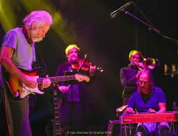 Bob Weir & Wolf Bros playing instruments on stage.