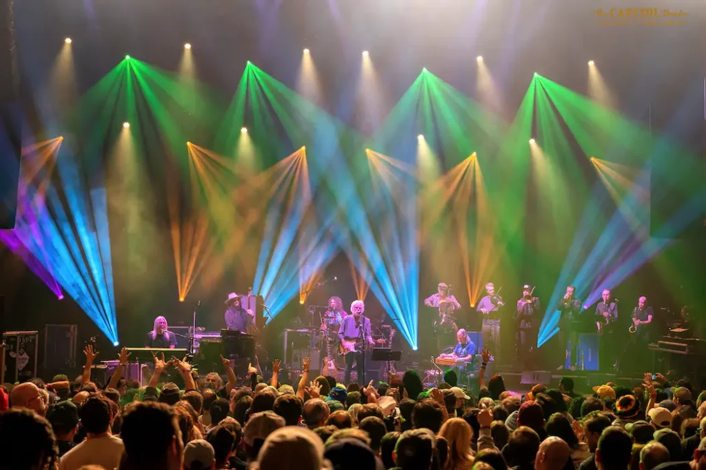 A group of people on stage with colorful lights.