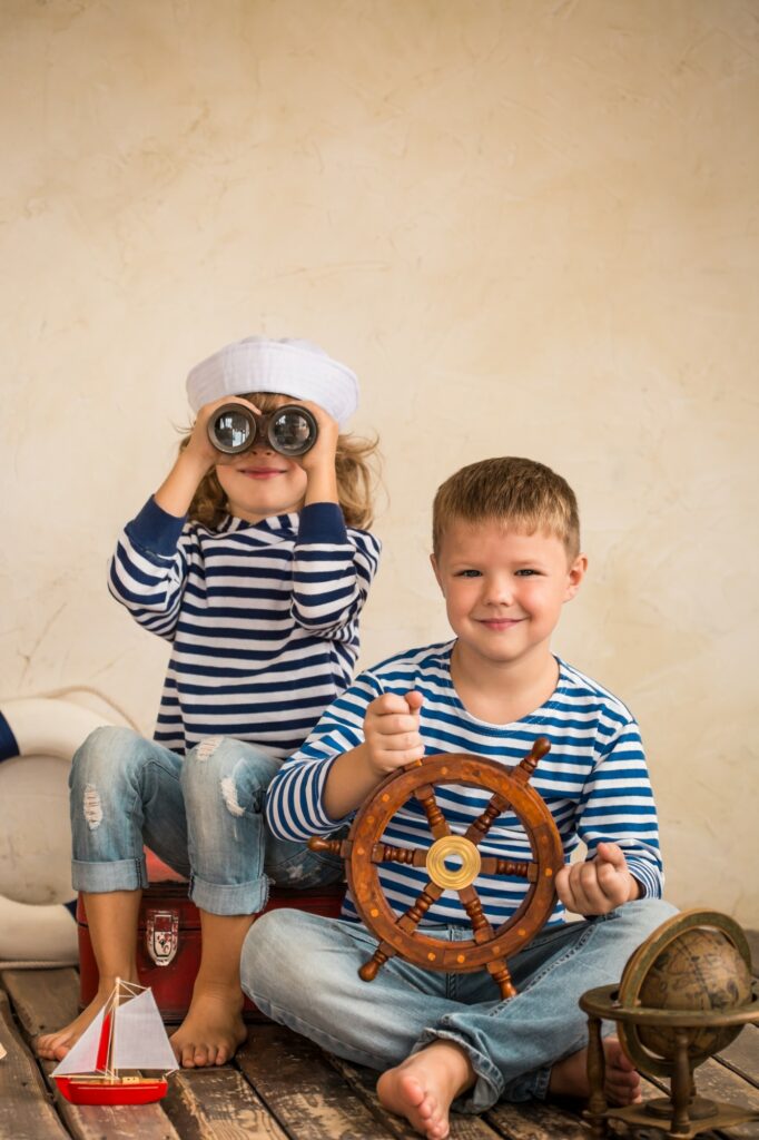 Two children in striped shirts and hats are sitting on a wooden floor during November's fun-filled adventures near Harbor Park Garage!