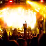 A crowd at a concert raises hands and makes the 