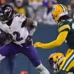 A Baltimore Ravens player runs with the football while being pursued by Green Bay Packers defenders during an NFL game.