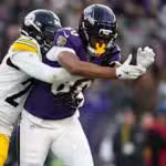 A Pittsburgh Steelers defender breaks up a pass intended for a Baltimore Ravens receiver during a football game.