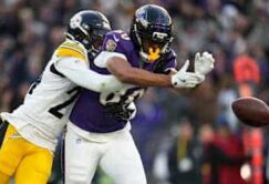 A Pittsburgh Steelers defender breaks up a pass intended for a Baltimore Ravens receiver during a football game.