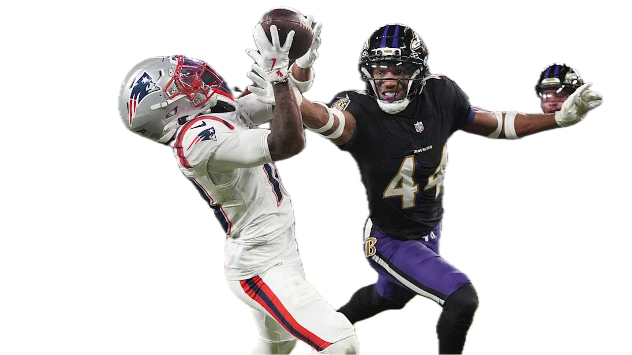 A football player in a Patriots uniform catches a pass while a Ravens defender attempts to block him during a game.